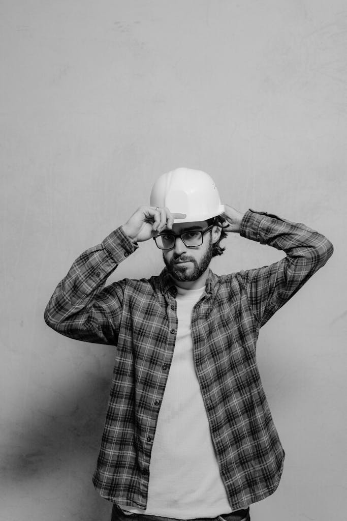 Black and white photo of a male construction worker wearing a hard hat and glasses.