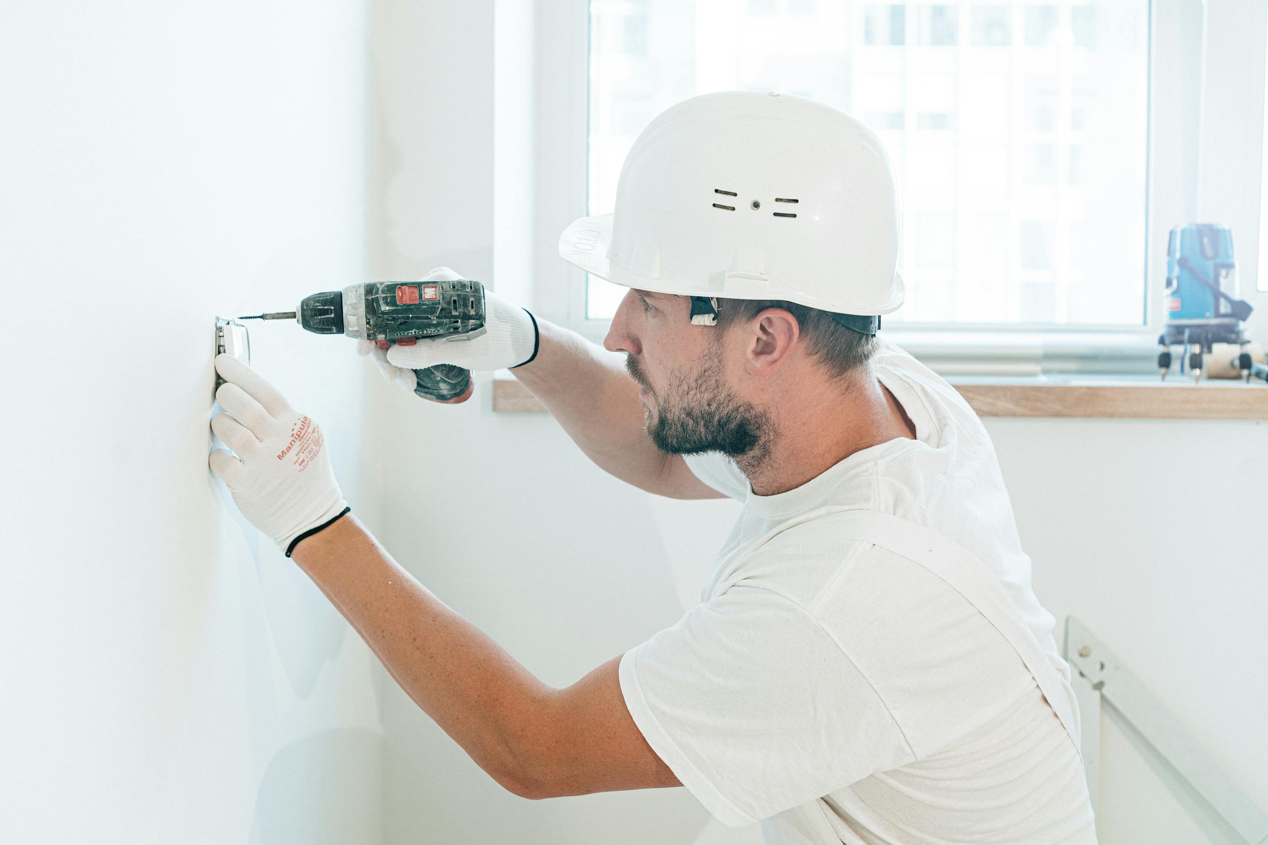 Carpenter skillfully uses a drill wearing safety gear during a renovation project indoors.